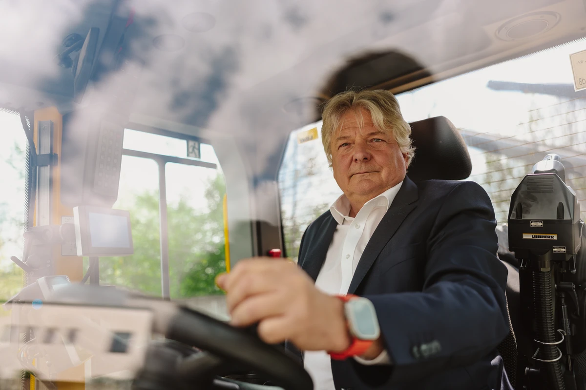Mann im Anzug sitzt am Steuer eines Baufahrzeugs.