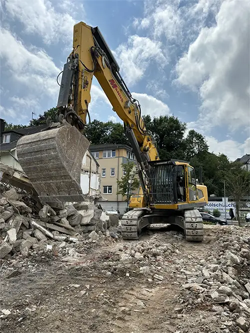 Gelber Kettenbagger beim Abbruch eines Gebäudes auf einer Baustelle.